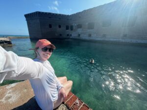 Dry Tortugas National Park: Our Half-Day, Seaplane Experience sitting on the edge of the fort at fort jefferson in dry tortugas national park smiling selfie with a pelican in the water